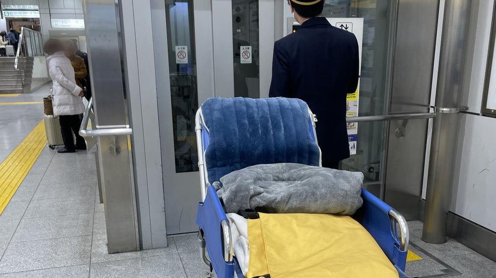 東京駅構内のエレベーターで、駅係員の誘導を受けながらストレッチャーを運ぶようす